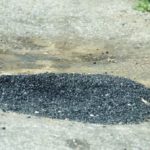 bache-reparado-con-grava-y-alquitrán-un-en-el-medio-de-la-carretera-calle-o-que-ha-sido-193417641